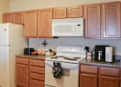 Thumbnail 3 of 18 - A kitchen with a white refrigerator, white oven, and wooden cabinets.