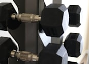 Thumbnail 6 of 18 - A set of hexagonal black dumbbells are on a rack.