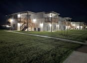 Thumbnail 10 of 16 - a large white house at night with a yard and stairs
