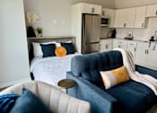 Thumbnail 20 of 35 - a bedroom with a bed and a couch and a kitchen
