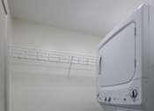 Thumbnail 8 of 18 - A white washing machine in a small laundry room.
