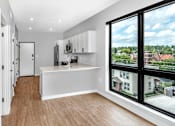 Thumbnail 25 of 35 - an empty living room with a large window and a kitchen