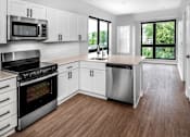 Thumbnail 24 of 35 - a white kitchen with stainless steel appliances and white cabinets