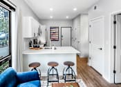 Thumbnail 4 of 35 - a kitchen with a white counter top and a bar with three stools