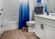 Thumbnail 11 of 35 - a white bathroom with a blue shower curtain and a toilet