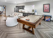 Thumbnail 22 of 35 - A pool table is in the middle of a room with a white couch and a wooden coffee table.