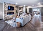 Thumbnail 19 of 35 - A modern living room with a stone wall and a large grey sofa.