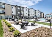 Thumbnail 16 of 35 - A sunny day at a residential complex with a pool and a patio area.