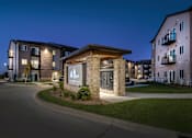Thumbnail 31 of 35 - A building with a sign that says "The Woodlands Apartments" is lit up at night.