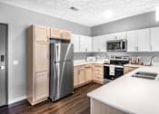 Thumbnail 2 of 35 - A kitchen with a refrigerator, microwave, oven, and sink.