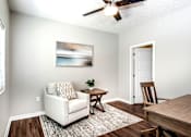 Thumbnail 11 of 35 - A living room with a white couch, a wooden coffee table, and a painting on the wall.