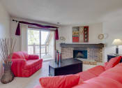 Thumbnail 30 of 35 - Living room in the one-bedroom model unit at Olde English Village, featuring a traditional stone-brick fireplace as a focal point.