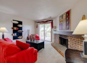 Thumbnail 28 of 35 - Living room in the one-bedroom model unit at Olde English Village, featuring a stone-brick fireplace and comfortable seating.