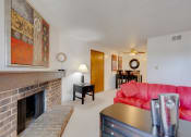Thumbnail 29 of 35 - One-bedroom model unit living room at Olde English Village, showcasing a stone-brick fireplace and warm, inviting decor.