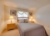 Thumbnail 31 of 35 - Bedroom in the one-bedroom model unit at Olde English Village, featuring a comfortable bed and natural light.