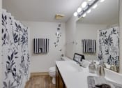 Thumbnail 25 of 35 - Bathroom in the two-bedroom model unit at Olde English Village, featuring a clean layout with a bathtub and ample storage.