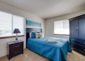 Thumbnail 20 of 35 - Bright bedroom in the two-bedroom model unit at Olde English Village, showcasing a large window and well-appointed furnishings.