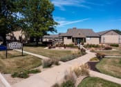 Thumbnail 1 of 35 - The Olde English Village clubhouse exterior is surrounded by well-maintained landscaping, creating a welcoming central gathering space for residents.