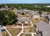 Thumbnail 5 of 35 - An aerial view of Olde English Village Apartments, nestled among the serene landscape, featuring a cluster of well-maintained buildings with courtyards and walkways.