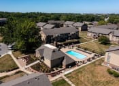 Thumbnail 4 of 35 - An aerial view of Olde English Village Apartments, nestled among the serene landscape, featuring a cluster of well-maintained buildings with courtyards and walkways.