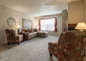 Thumbnail 12 of 16 - Cozy living room featuring neutral-colored furniture, a warm area rug, and a bright atmosphere with natural light coming through the windows.