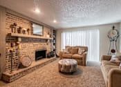 Thumbnail 12 of 17 - A cozy living room with a three-seater sofa, a love seat, a fireplace, a floor clock, and a round coffee table, softly lit with warm lighting for a relaxing atmosphere.