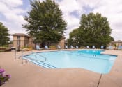 Thumbnail 9 of 17 - Outdoor swimming pool at Wilshire Apartments complex, surrounded by lounge chairs and landscaped greenery.