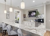 Thumbnail 20 of 32 - A kitchen with a marble countertop and grey chairs.