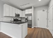 Thumbnail 3 of 28 - an empty kitchen with white cabinets and a black counter top
