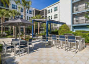 Thumbnail 16 of 69 - a patio with tables and chairs and umbrellas at an apartment building