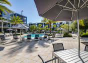Thumbnail 15 of 69 - a patio with tables chairs and umbrellas and a pool