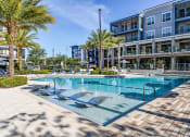 Thumbnail 11 of 69 - a large swimming pool in front of a building with palm trees