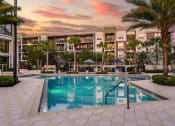 Thumbnail 21 of 69 - a swimming pool in front of an apartment building at sunset