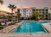 Thumbnail 22 of 69 - a swimming pool in front of an apartment building at sunset