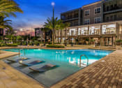 Thumbnail 26 of 69 - a swimming pool in front of a building with palm trees