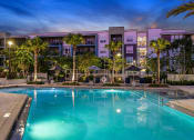 Thumbnail 25 of 69 - a swimming pool at night with a hotel in the background