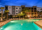 Thumbnail 24 of 69 - a large swimming pool in front of an apartment building at night