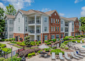 Thumbnail 6 of 43 - A large apartment complex with a pool and patio area.