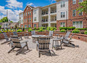 Thumbnail 5 of 43 - A patio with chairs and a table in front of apartment buildings.