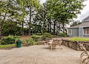 Thumbnail 8 of 25 - A backyard with a stone wall and a table set for four.