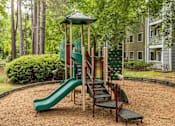 Thumbnail 10 of 25 - A playground with a green slide and a red and green play structure.