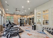Thumbnail 17 of 39 - A gym with a brick wall and a row of treadmills.