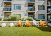 Thumbnail 31 of 51 - a row of adirondack chairs on a lawn in front of an apartment building at Indigo 301 Apartments, Pennsylvania, 19406