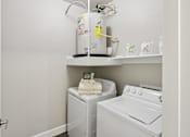 Thumbnail 32 of 39 - A white washing machine and dryer in a small laundry room.