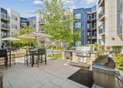 Thumbnail 34 of 51 - an outdoor patio with a grill and tables with umbrellas at Indigo 301 Apartments, Pennsylvania, 19406