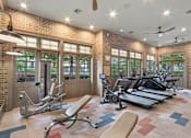 Thumbnail 18 of 39 - A gym with a brick wall and a variety of exercise equipment.