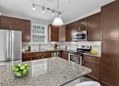 Thumbnail 29 of 39 - A kitchen with brown cabinets and a granite countertop.