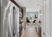Thumbnail 19 of 39 - A modern kitchen with a stainless steel refrigerator and wooden flooring.