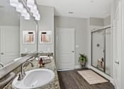 Thumbnail 23 of 39 - A bathroom with a sink, mirror, and wooden floor.