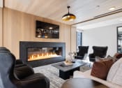 Thumbnail 24 of 65 - a living room with leather chairs and a fireplace at Stonehill at West Orange, West Orange, New Jersey